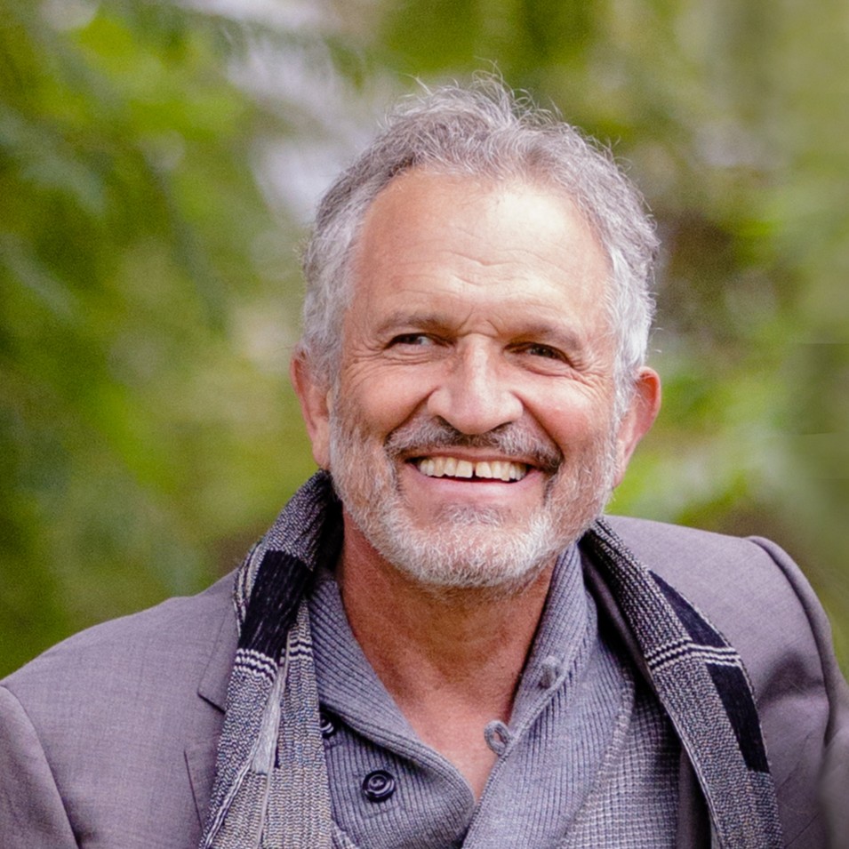 Michael Lehrer headshot in grey blazer and scarf.