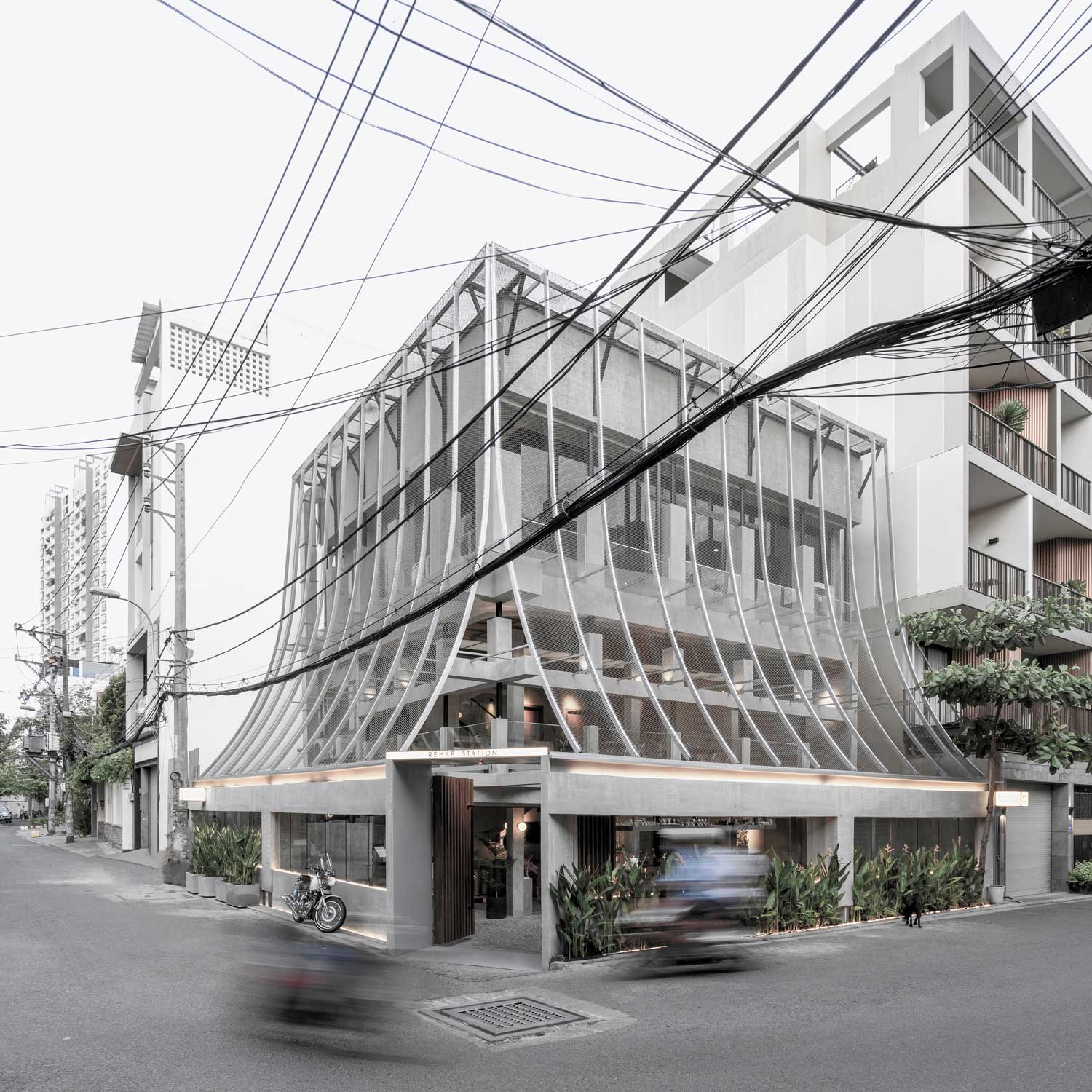 White building with mesh screen sloping toward street