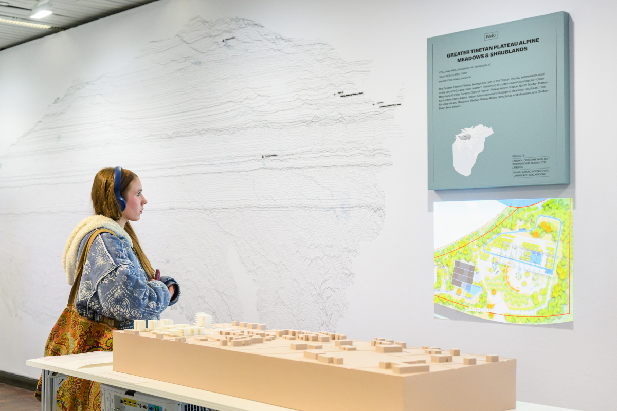 A person viewing a wall display of a topographical map and video projection.