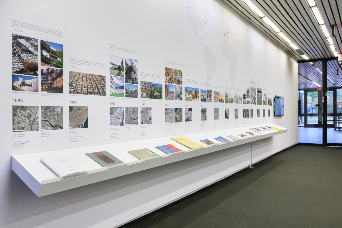 A wall displaying a large map of the world and a timeline of images above a shelf of books.