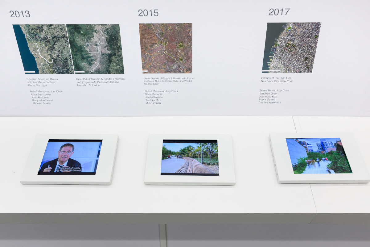 Detail of the exhibit showing satellite images of various landscapes and three screens of videos.