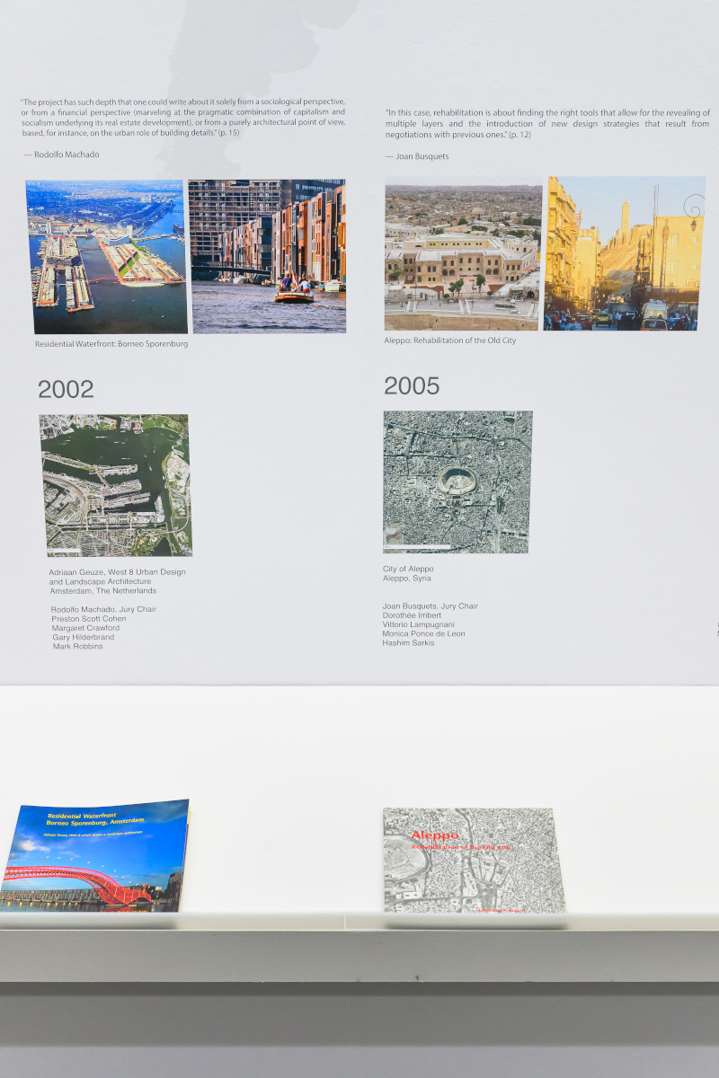 Detail of the exhibit showing images of urban design projects above a shelf with books.