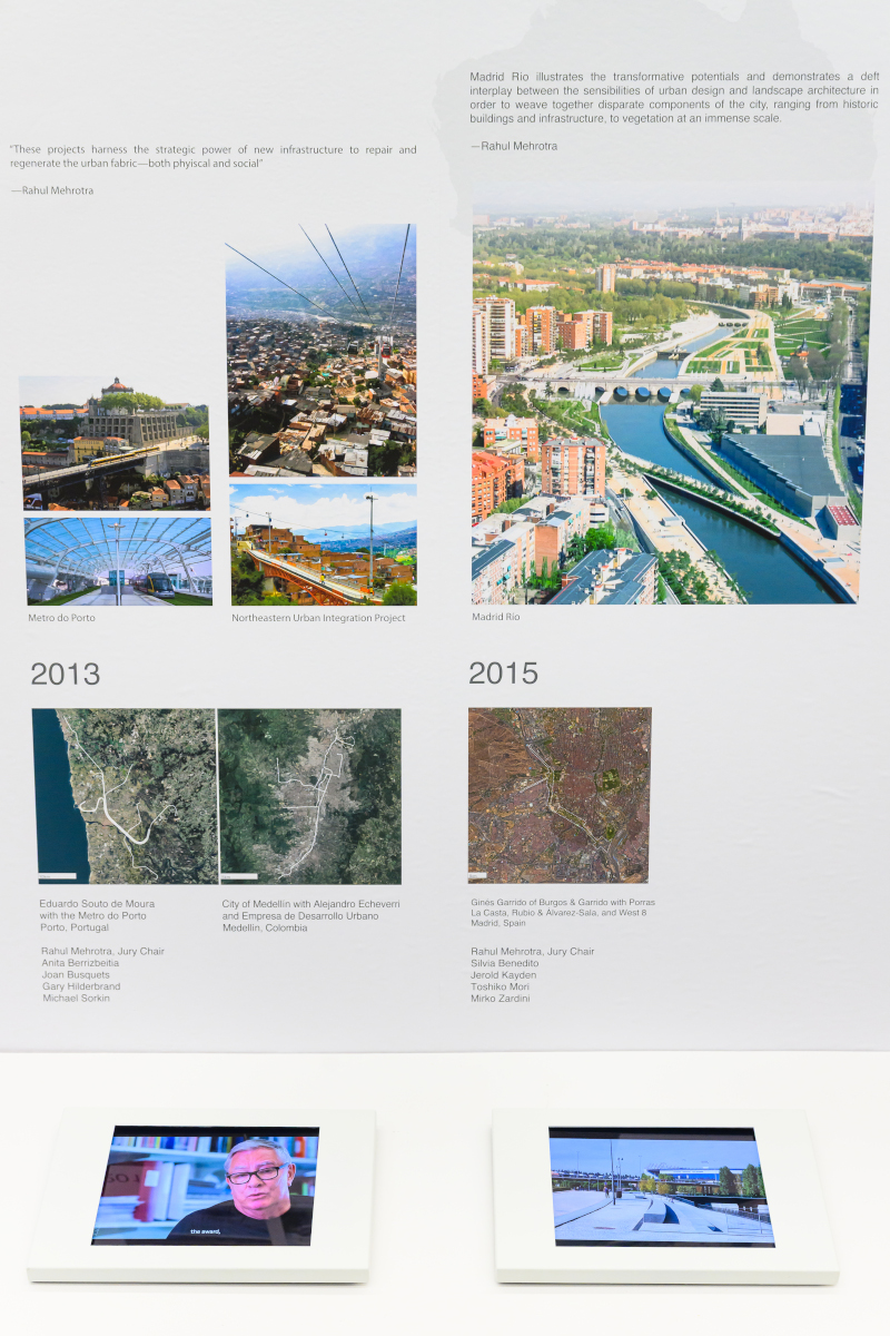 Detail of the exhibit showing images of urban design projects above a shelf with video screens.