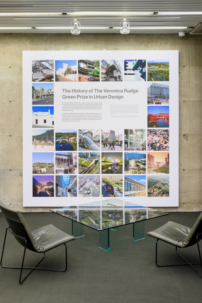 A seating area in front of a wall with a photo collage of urban design projects from around the world.