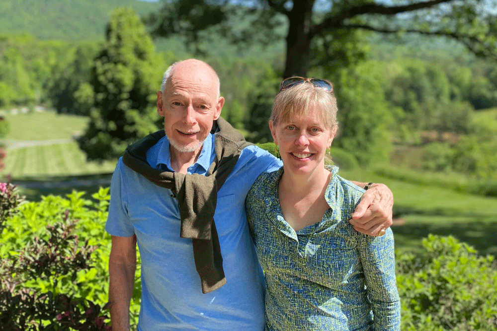 Husband and wife stand side by side outdoors