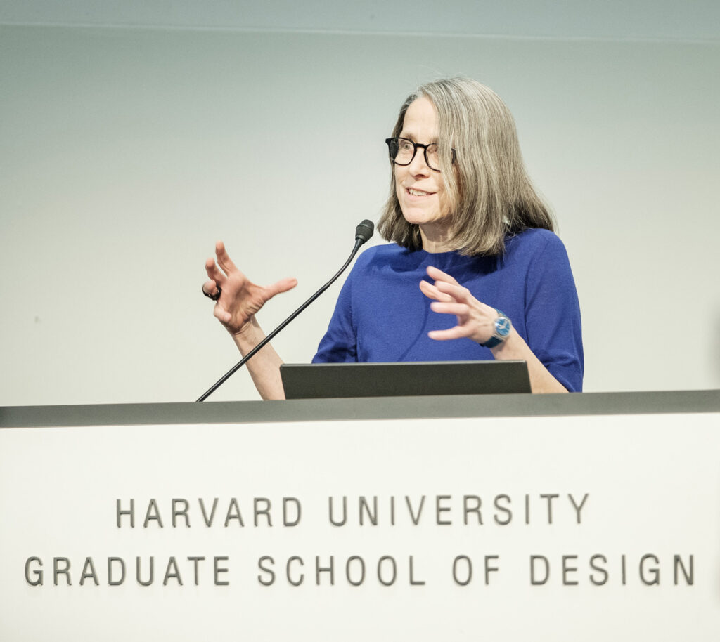 Woman in blue shirt talks at podium.