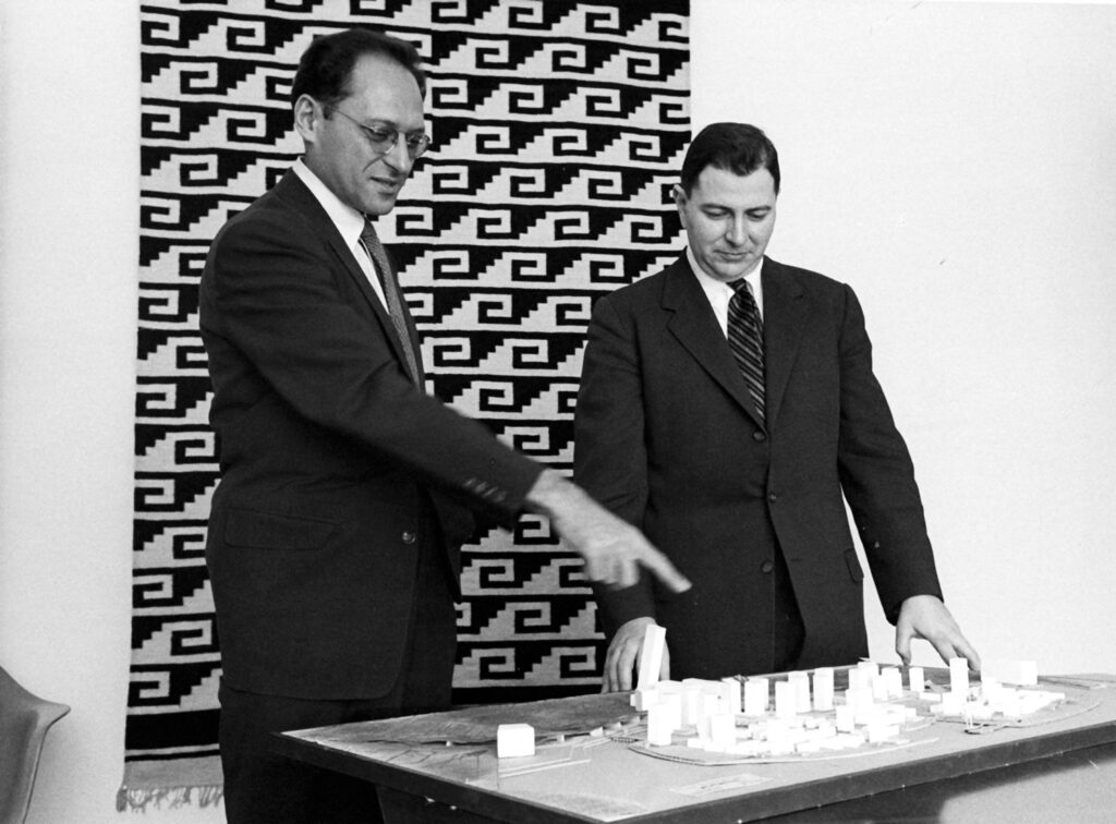 Two men point at model of an ideal city around 1960.