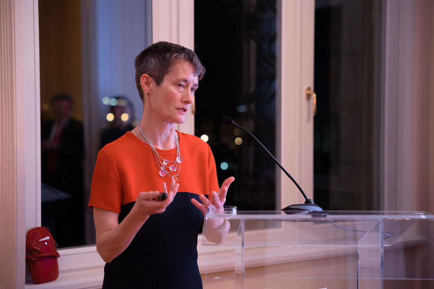 Woman in red and black dress talking at a podium