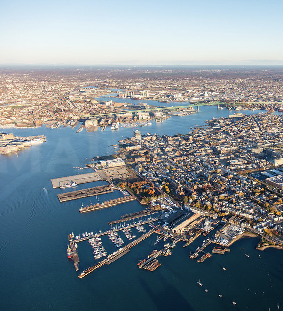 Aerial view of East Boston showing a densely built area with multiple piers jutting out into the harbor.