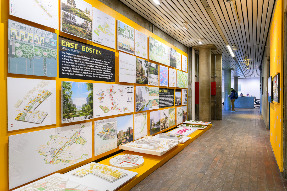 A wall displaying a variety of images with landscape and architectural models below.