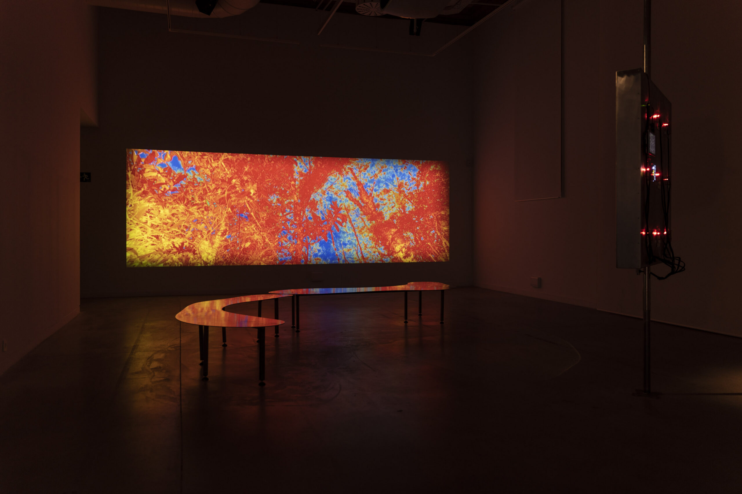 An installation shot of an abstract image projected on a horizontal screen in a gallery.