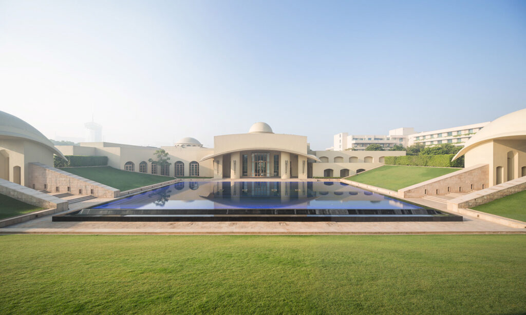Grand white architecture with reflecting pool and grass.