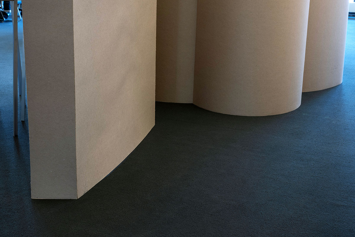 A temporary wall made of chipboard formed into multiple curves and corners.