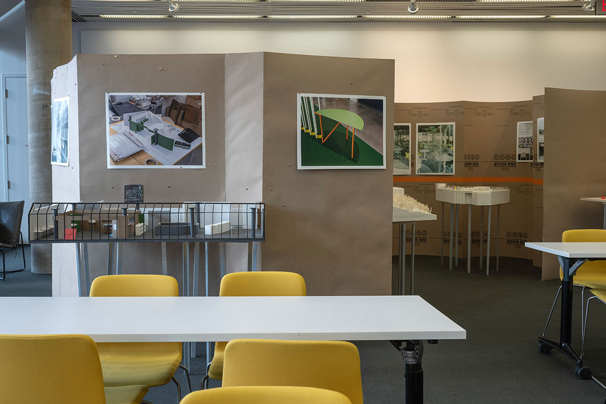 Several curved and shaped temporary walls made of chipboard in Frances Loeb Library, with architectural models and images on display.