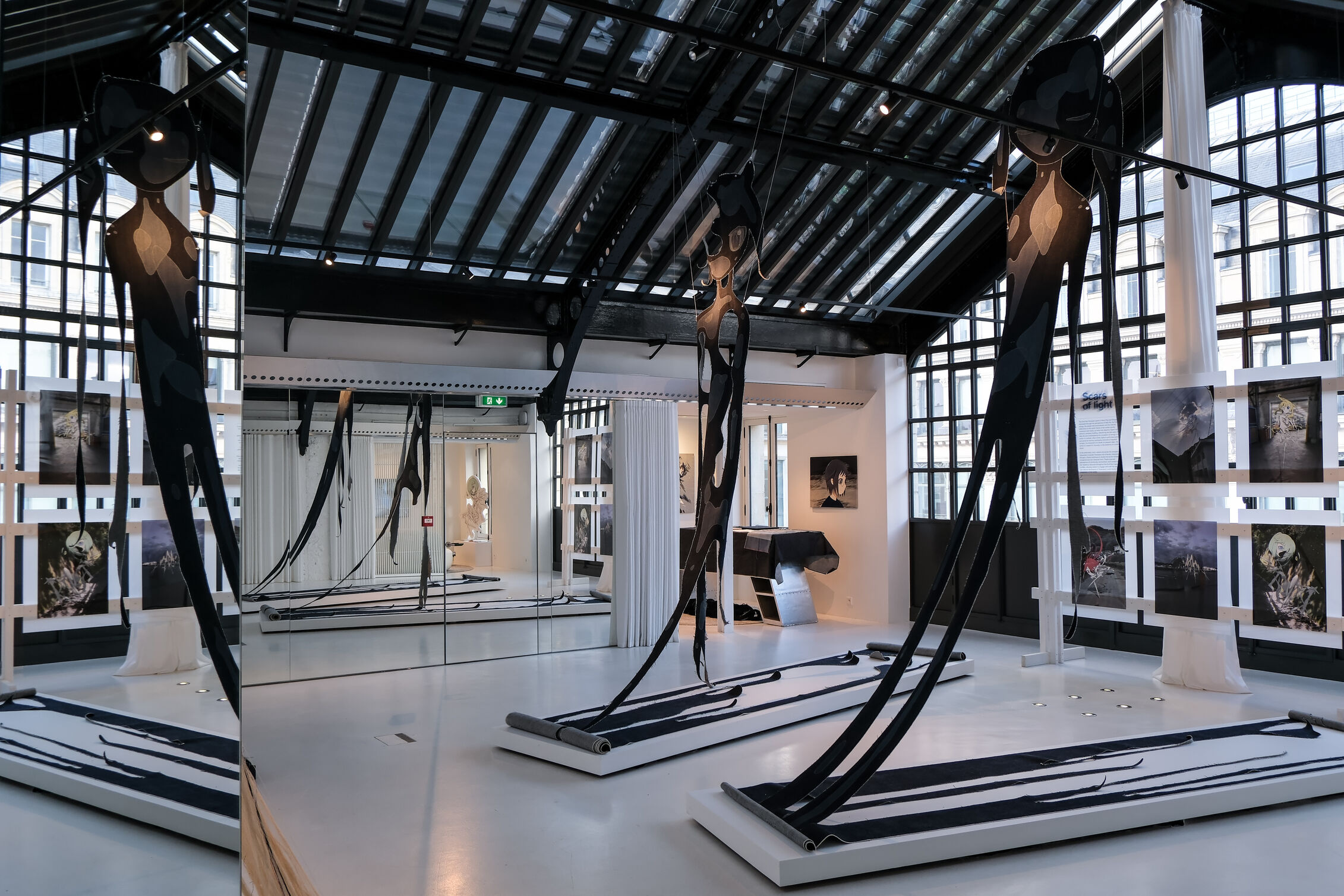 Large woven textile artworks suspended across from each other in a minimalist gallery