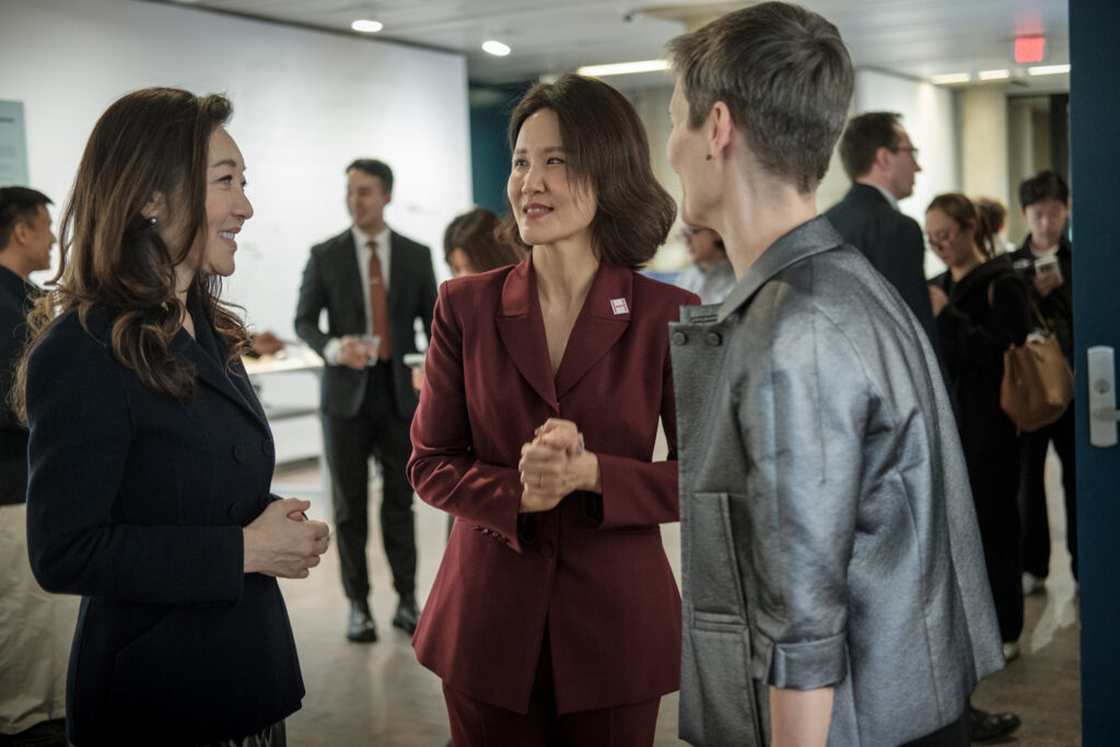 Three women talk at an exhibition opening.