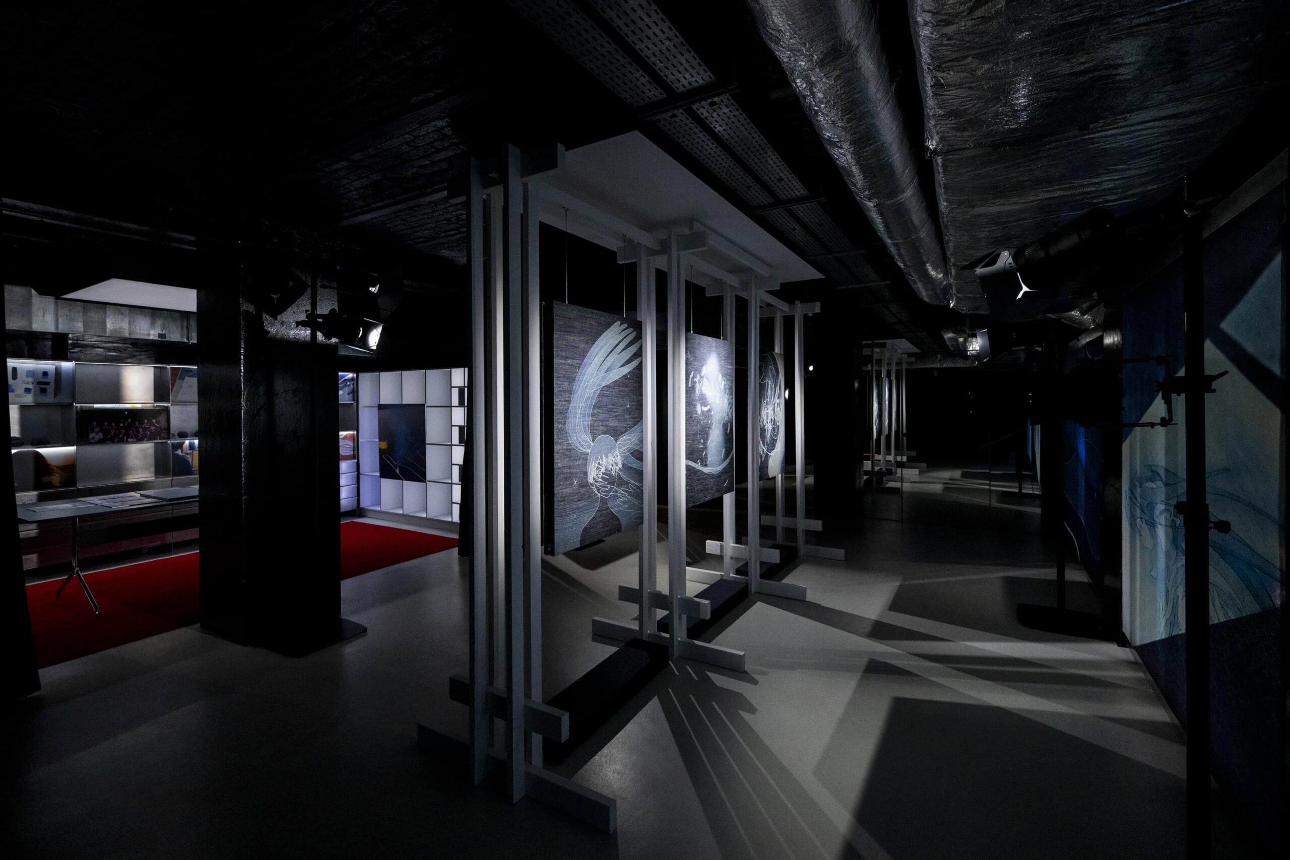 Three denim etched artworks hang in a dark room