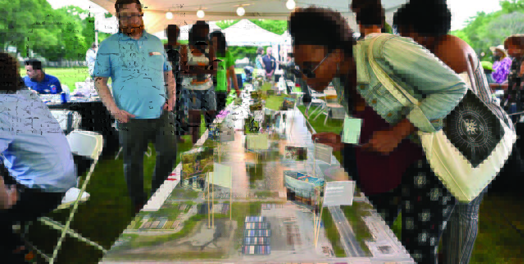 A woman studies a table at an outdoor market or information session.