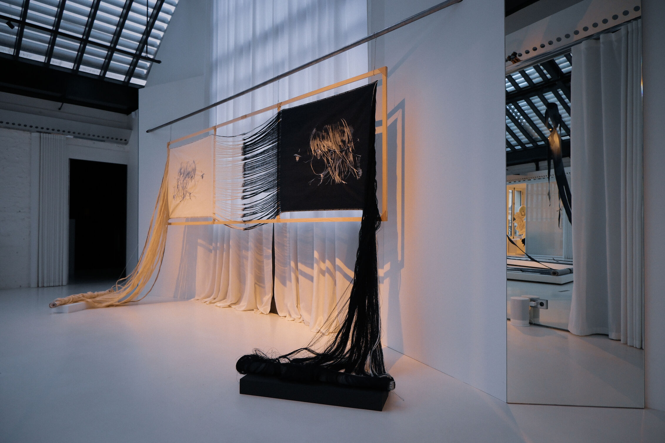 Large woven textile artwork suspended in a minimalist gallery