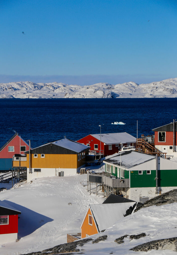 Colorful houses near water and snowy mountains.