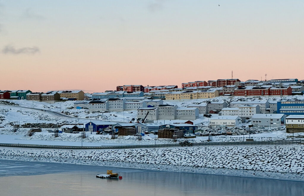 View of city with colorful houses across frozen water.