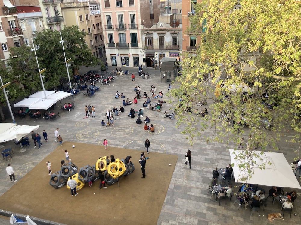 Aerial view of the Plaza del Sol in Barcelona on a sunny day, with people sitting in the plaza. "Aerial view of Plaza del Sol in Barcelona" by Mattsjc is licensed under CC BY 4.0.