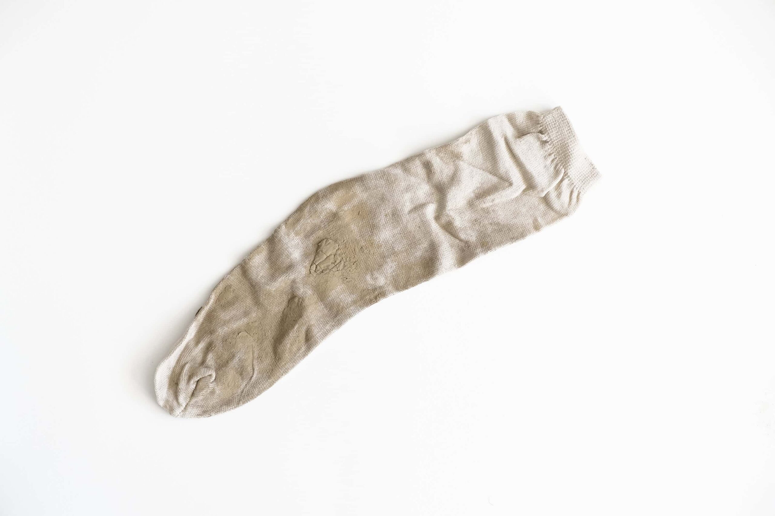 A white sock with bits of dried mud on the surface