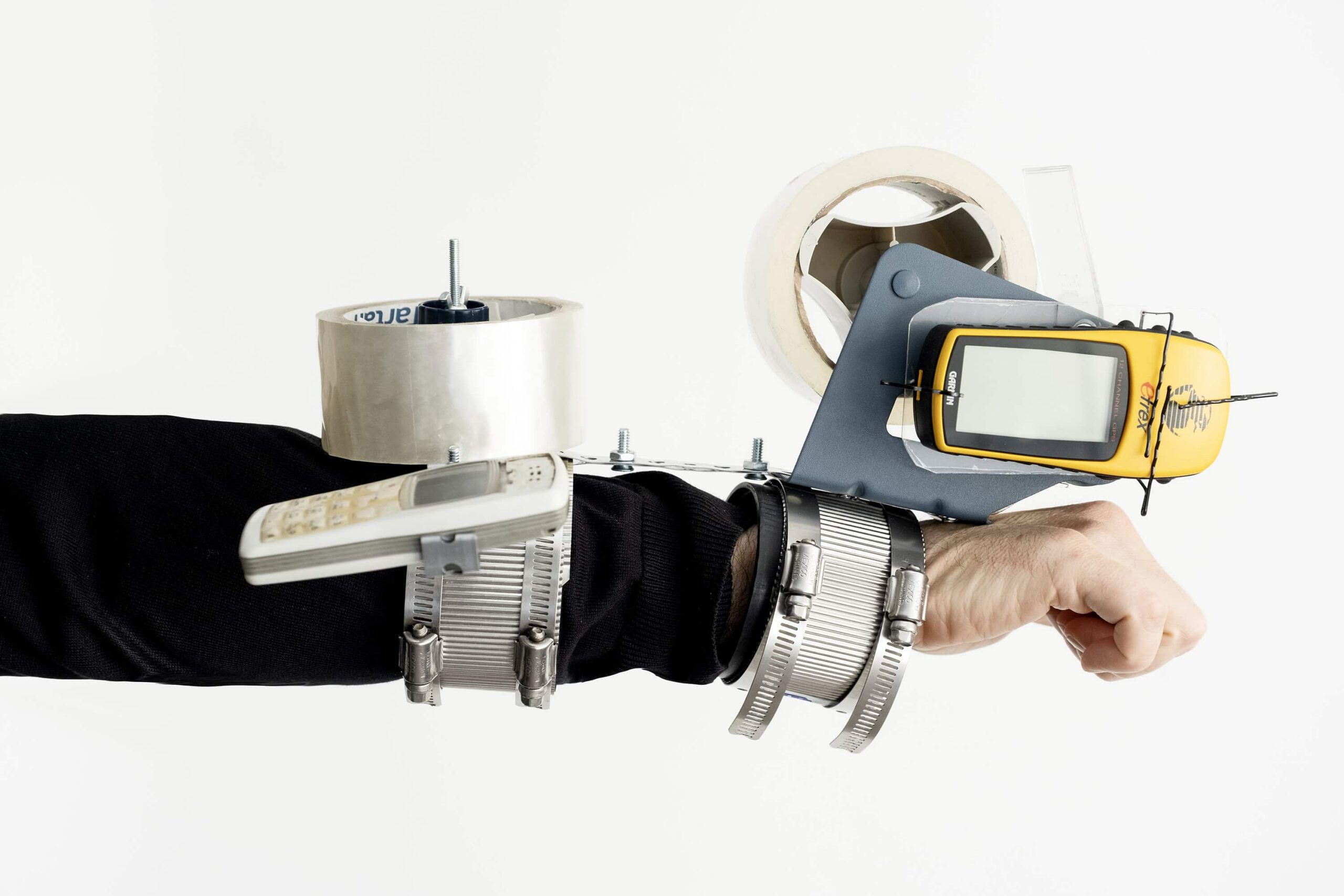 A right arm in a black sleeve with metal cuffs which attach a device that uses packing tape to collect soils and sediments