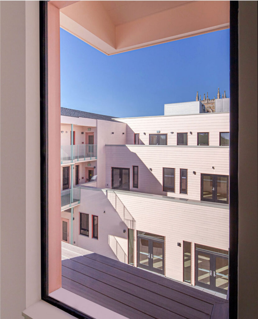 View of pink housing complex through window.