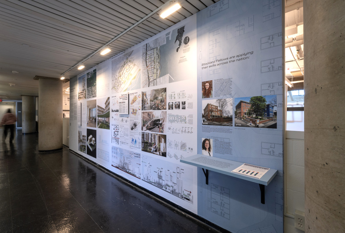 A long wall displaying multiple images of design projects and a shelf with a pamphlet.