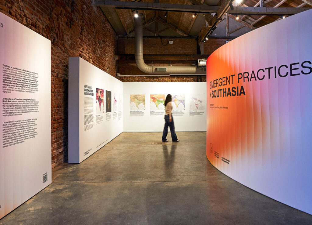 A woman walking between curved walls with images.