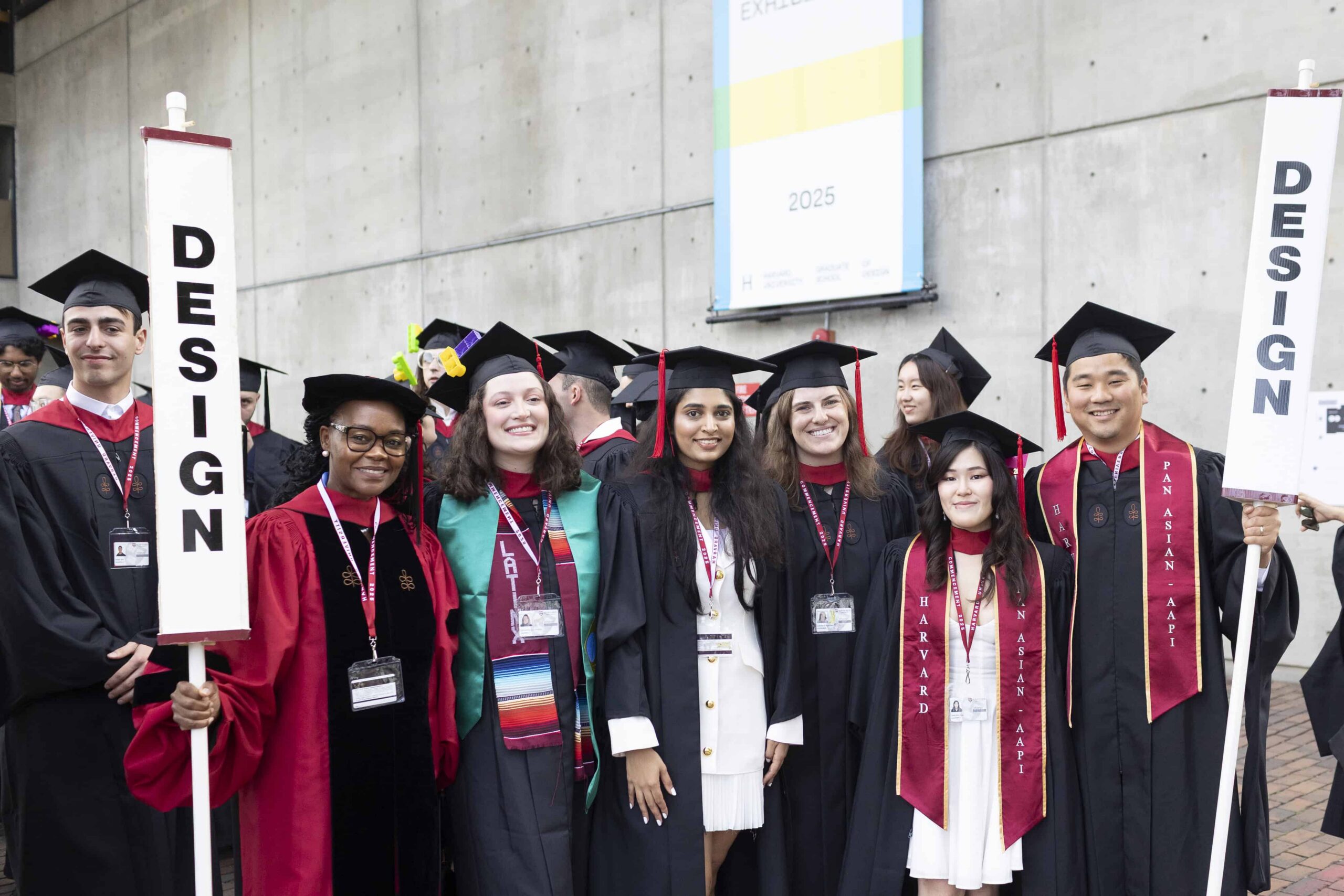 Students in Commencement attire walking but Gund Hall.