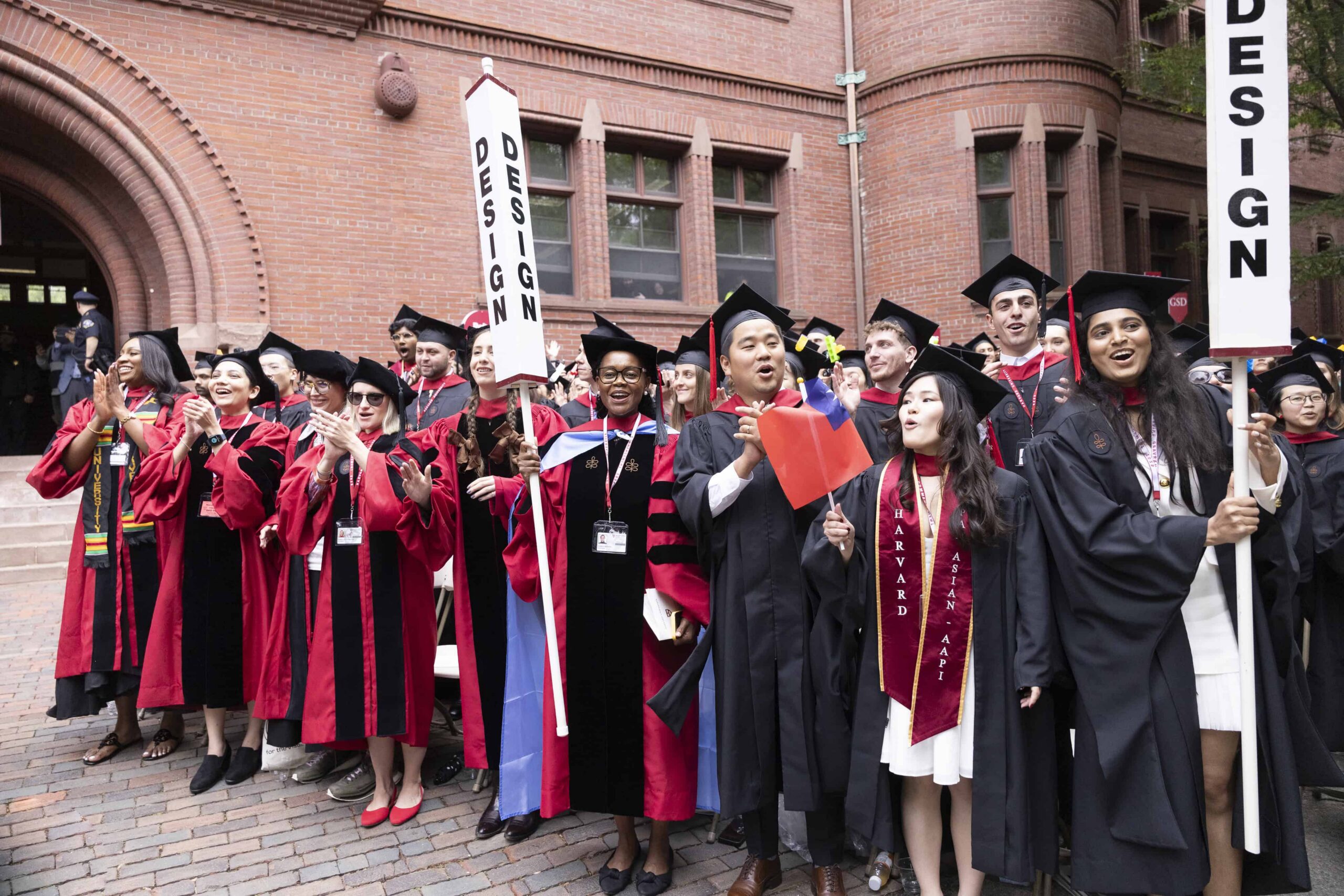 Students at Commencement holding design sign.