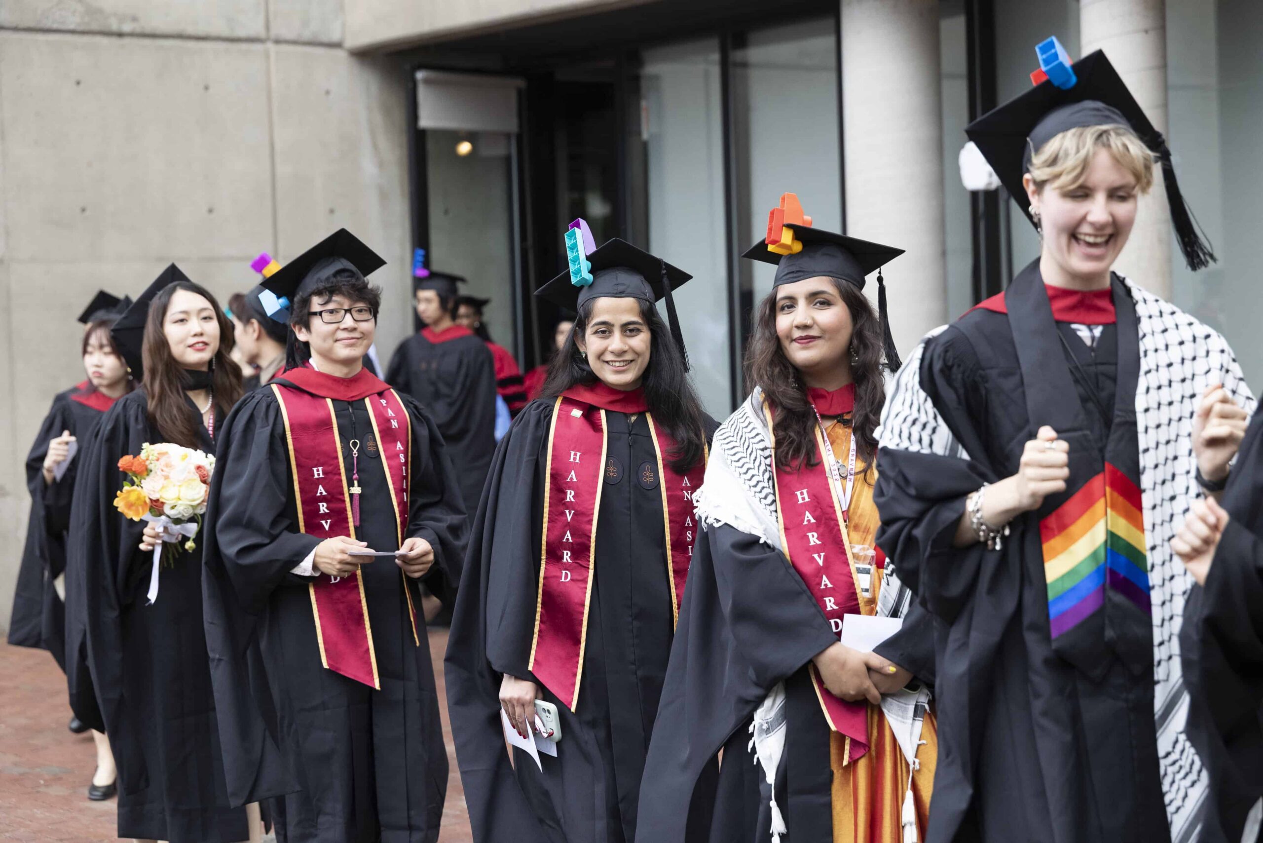 Students in Commencement attire walking but Gund Hall.