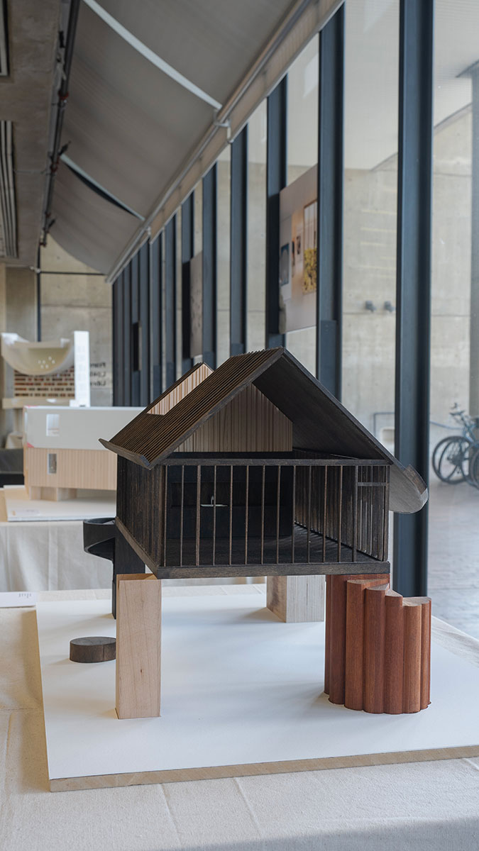 A wooden architectural model supported by wooden pillars in a variety of shapes.