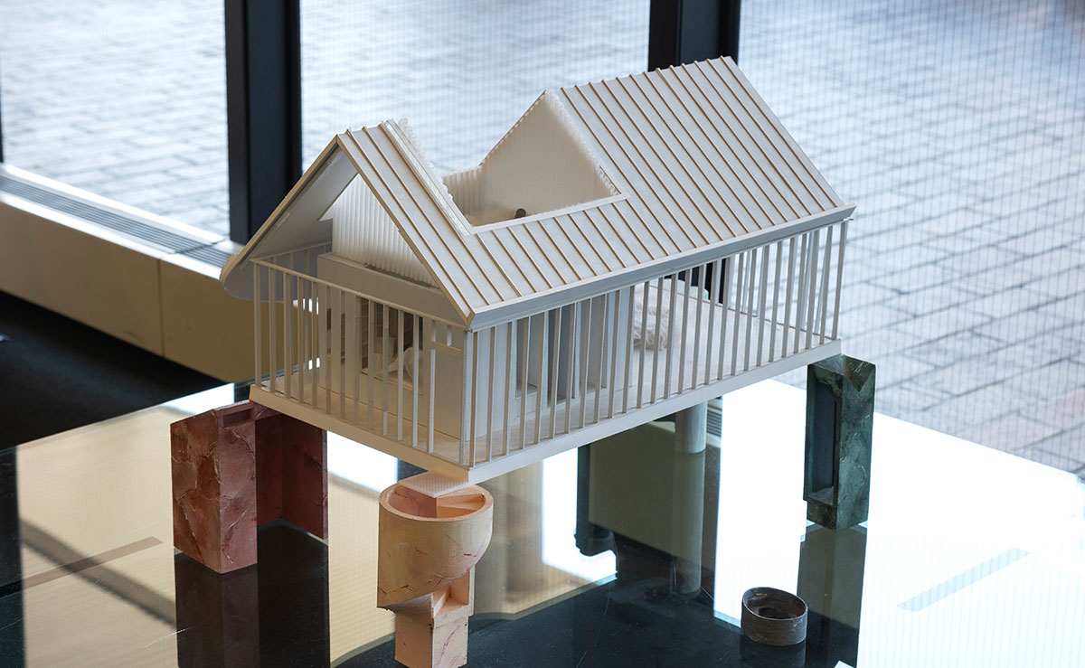A white architectural model supported by pillars in various different shapes and colors.