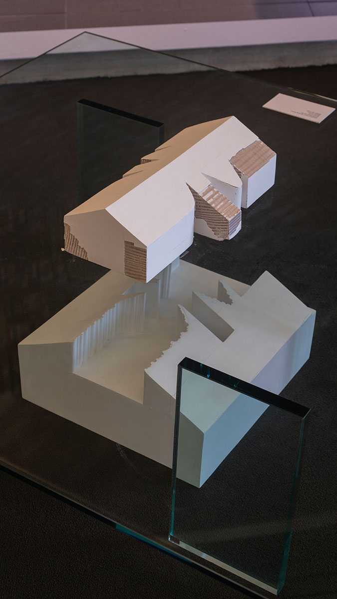 An architectural model in two pieces displayed above and below a glass tabletop.