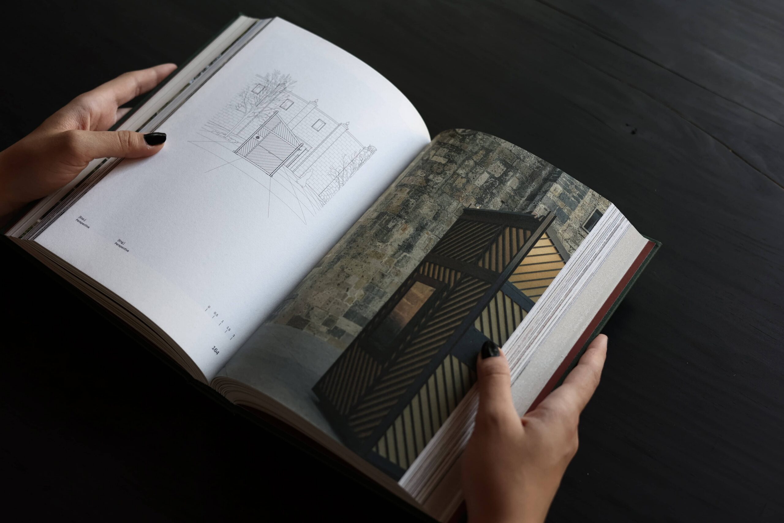 Two hands flip through a book with architectural images