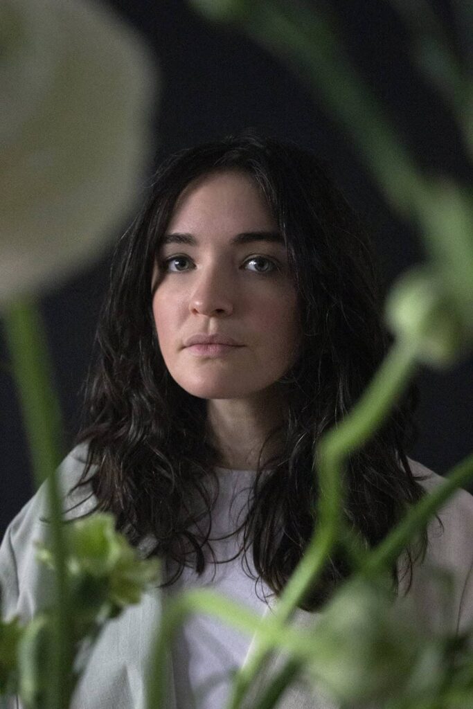 Sonia Sobrino Ralston, looking at the camera with some plants in the foreground.