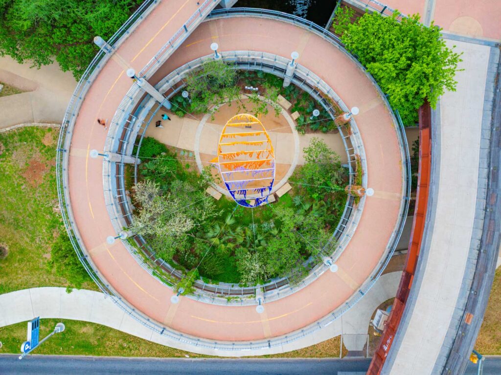 A ring suspended in a circular bridge entry in Austin and adorned with multi-color fabrics.
