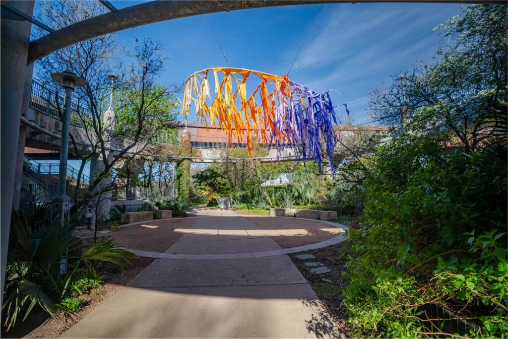 A ring suspended in a circular bridge entry in Austin and adorned with multi-color fabrics.