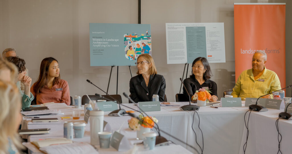 Women sitting and talking at a table at a symposium.