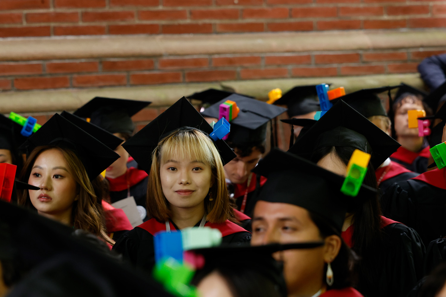 A group of students in commencement regalia, each cap adorned with brightly colored legos.