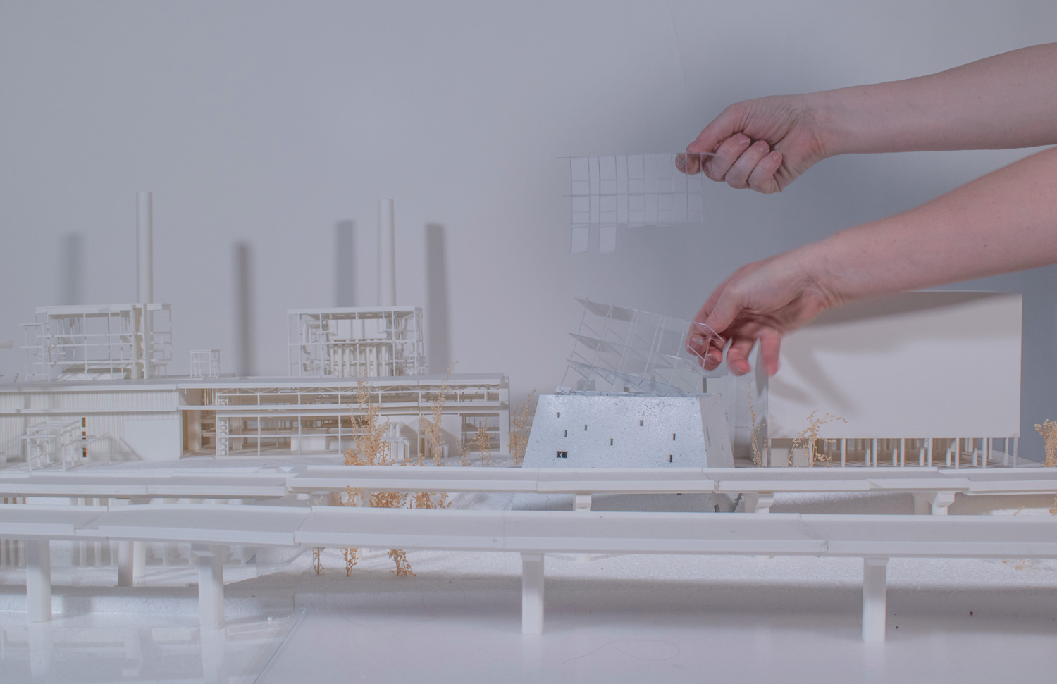 Model of wood, plexiglass, with hands placing an element.