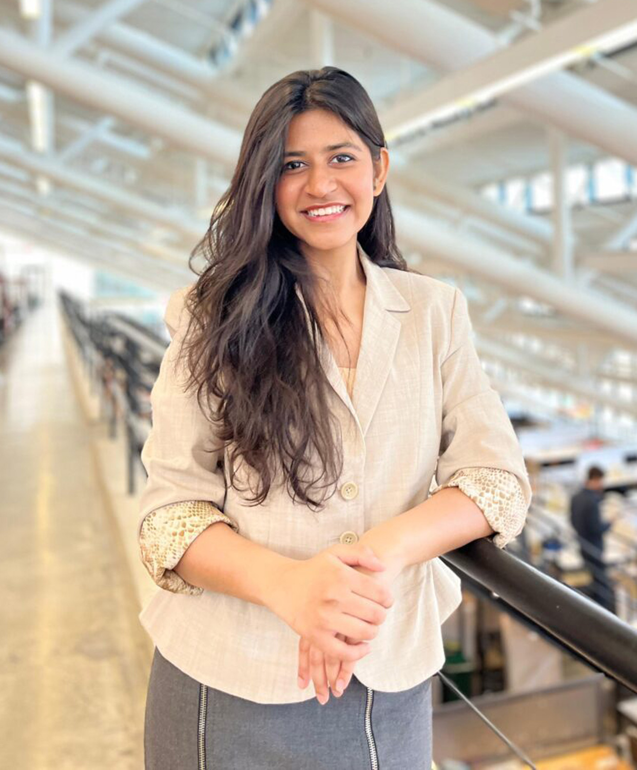 Woman stands leaning on railing and smiling.