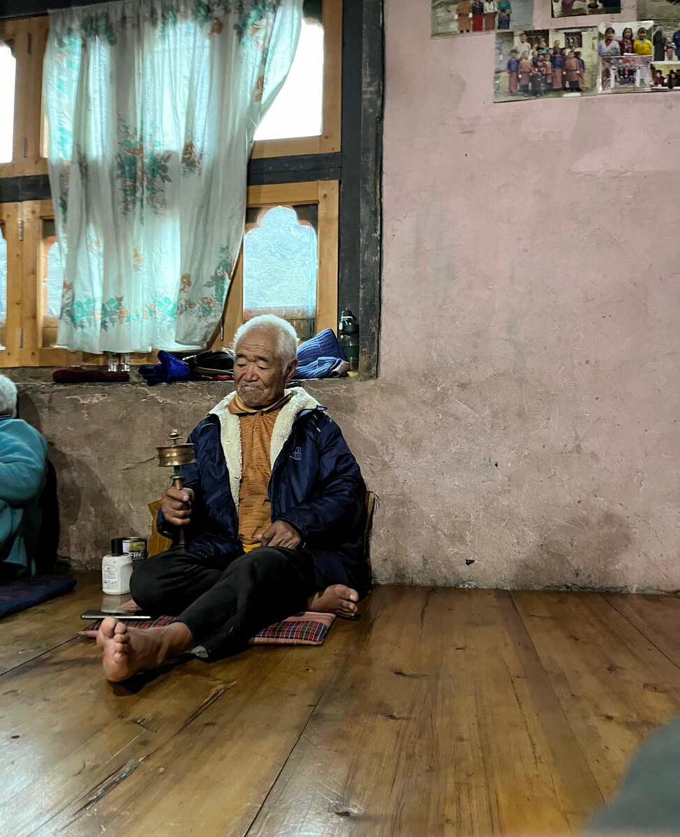 An older Bhutanese resident holding a prayer wheel