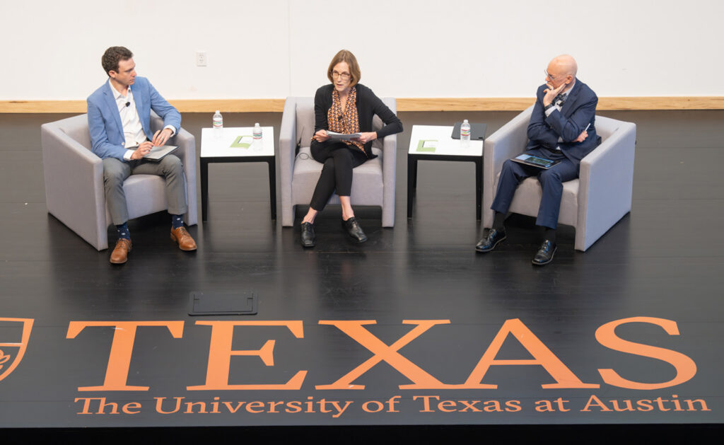 Two men and one woman on stage at an event.