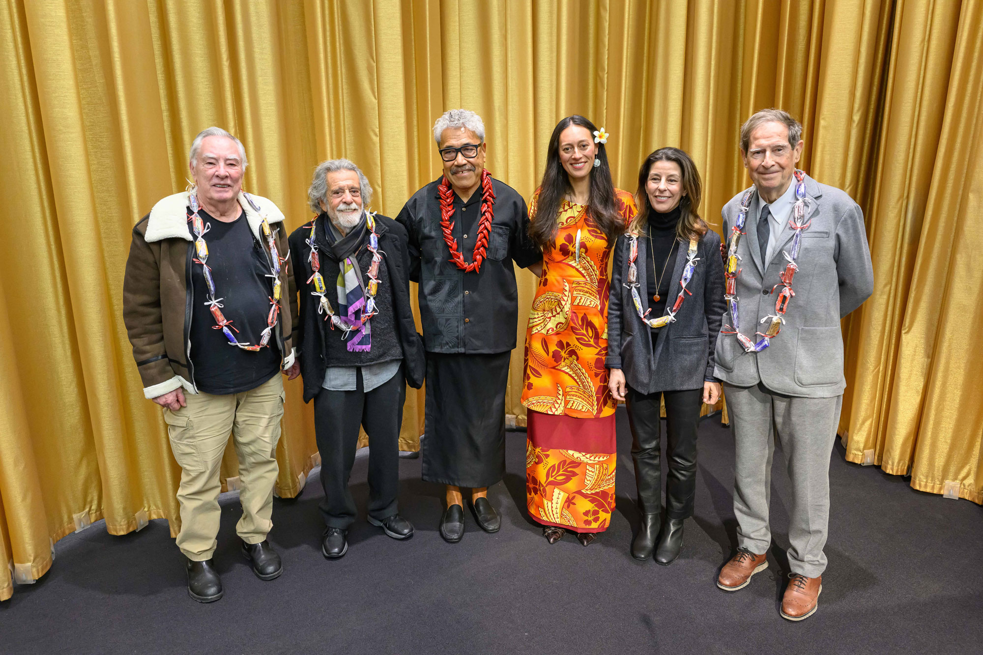 Group photo from - 2026 Druker Fellowship presentation featuring Elyjana Roach (MAUD ’22) presentation standing with faculty, Ron and Kimberly Druker and guest speakers in front of gold curtain