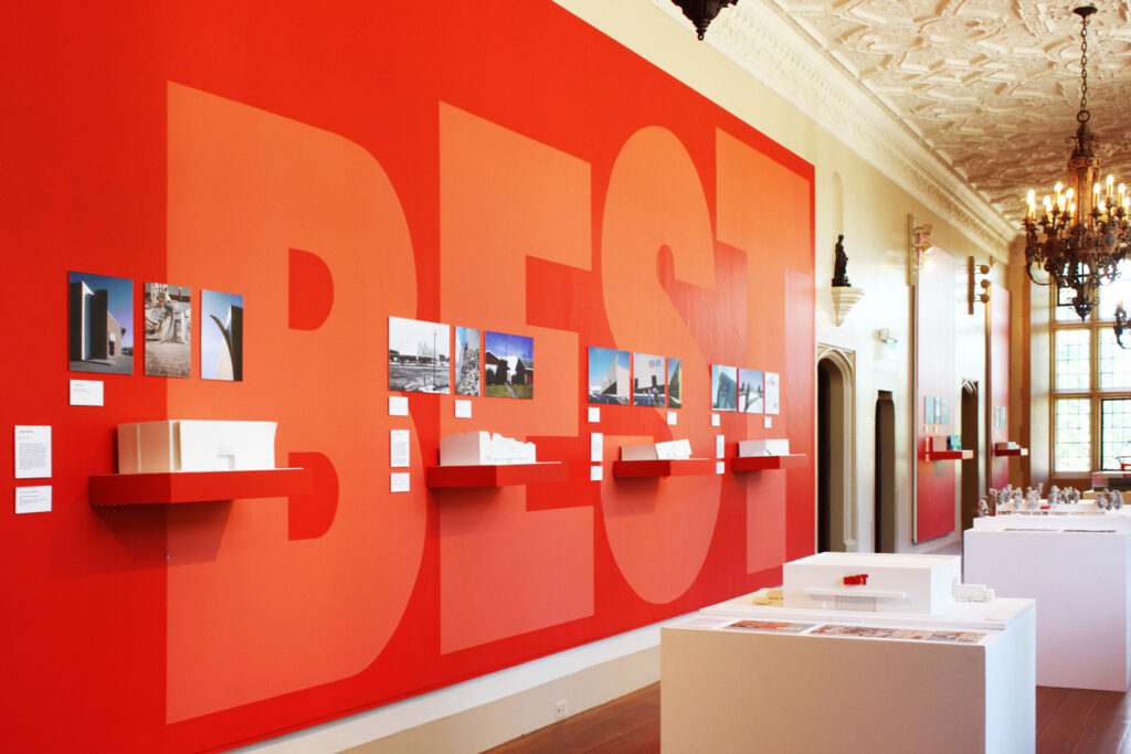 Photos and models against red wall.