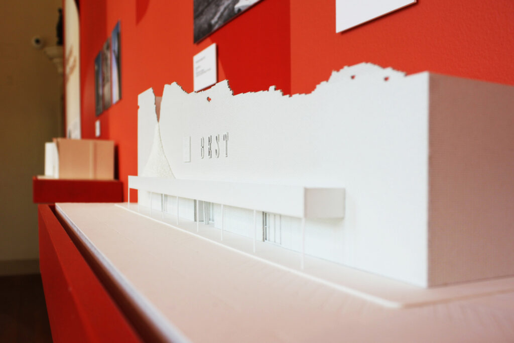 White building model against red wall.